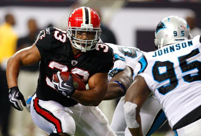 ATLANTA - SEPTEMBER 20:  Michael Turner #33 of the Atlanta Falcons rushes upfield against Charles Johnson #95 of the Carolina Panthers at Georgia Dome on September 20, 2009 in Atlanta, Georgia.  (Photo by Kevin C. Cox/Getty Images)