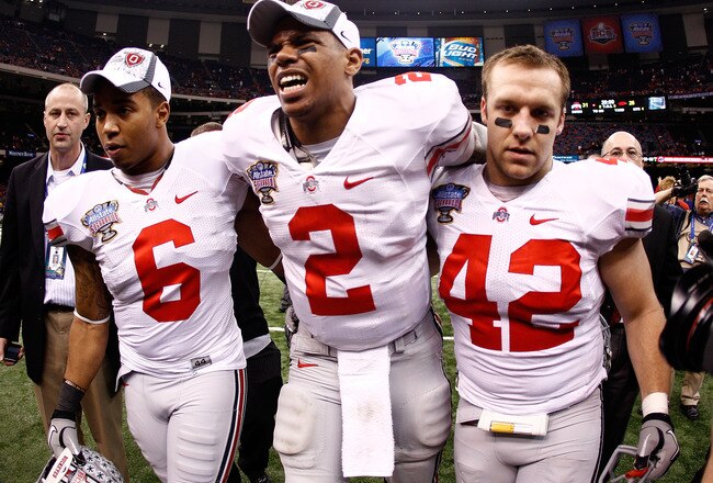 NEW ORLEANS, LA - JANUARY 04:  (M) Quarterback Terrelle Pryor #2 of the Ohio State Buckeyes is helped off the field by teammates Etienne Sabino #6 and Andrew Sweat #42 after the Buckeyes 31-26 victory against the Arkansas Razorbacks during the Allstate Sugar Bowl at the Louisiana Superdome on January 4, 2011 in New Orleans, Louisiana.  (Photo by Chris Graythen/Getty Images)