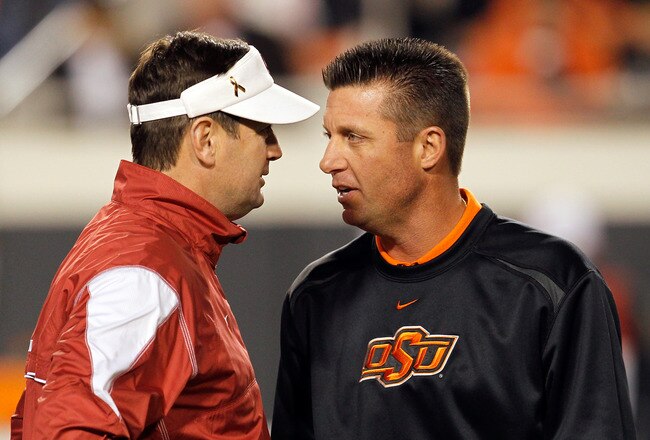 STILLWATER, OK - NOVEMBER 27:  Head coach Bob Stoops (L) of the Oklahoma Sooners talks with head coach Mike Gundy (R) of the Oklahoma State Cowboys at Boone Pickens Stadium on November 27, 2010 in Stillwater, Oklahoma.  (Photo by Tom Pennington/Getty Images)