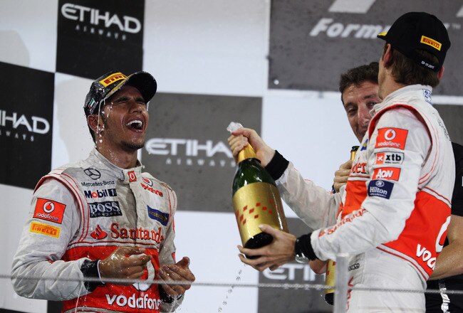 ABU DHABI, UNITED ARAB EMIRATES - NOVEMBER 13:  Race winner Lewis Hamilton (L) of Great Britain and McLaren celebrates on the podium with third placed Jenson Button (R) of Great Britain and McLaren following the Abu Dhabi Formula One Grand Prix at the Yas Marina Circuit on November 13, 2011 in Abu Dhabi, United Arab Emirates.  (Photo by Mark Thompson/Getty Images)