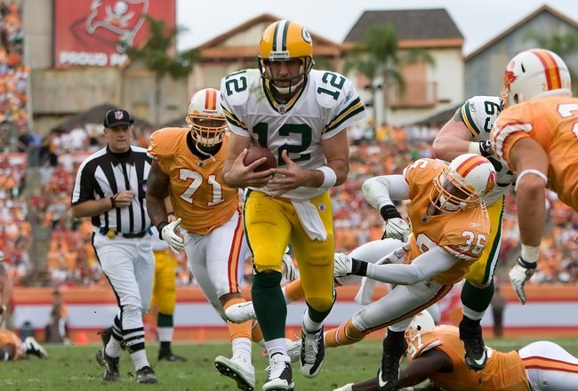 TAMPA, FL - NOVEMBER 08:  Quarterback Aaron Rodgers #12 of the Green Bay Packers scores a fourth quarter touchdown as defenders Barrett Ruud #51 and Sabby Piscatelli #21 of the Tampa Bay Buccaneers deliver a hit during the game at Raymond James Stadium on November 8, 2009 in Tampa, Florida. The Buccaneers defeated the Packers 38-28.  (Photo by J. Meric/Getty Images)