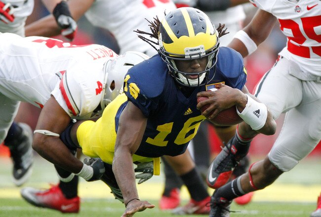 ANN ARBOR, MI - NOVEMBER 26:  Denard Robinson #16 of the Michigan Wolverines dives for extra yards past C.J. Barnett #4 of the Ohio State Buckeyes at Michigan Stadium on November 26, 2011 in Ann Arbor, Michigan. Michigan won the game 40-34. (Photo by Gregory Shamus/Getty Images)
