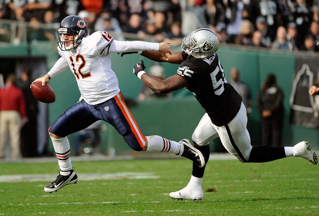 OAKLAND, CA - NOVEMBER 27:  Caleb Hanie #12 of the Chicago Bears runs with the ball stiff arming Rolando McClain #55 of the Oakland Raiders at O.co Coliseum on November 27, 2011 in Oakland, California.  (Photo by Thearon W. Henderson/Getty Images)