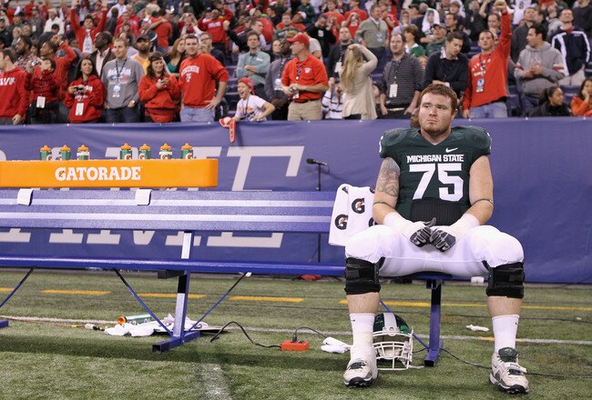 INDIANAPOLIS, IN - DECEMBER 03:  Jared McGaha #75 of the Michigan State Spartans sits alone on the bench dejected after they lost 42-39 against the Wisconsin Badgers during the Big 10 Conference Championship Game at Lucas Oil Stadium on December 3, 2011 in Indianapolis, Indiana.  (Photo by Andy Lyons/Getty Images)