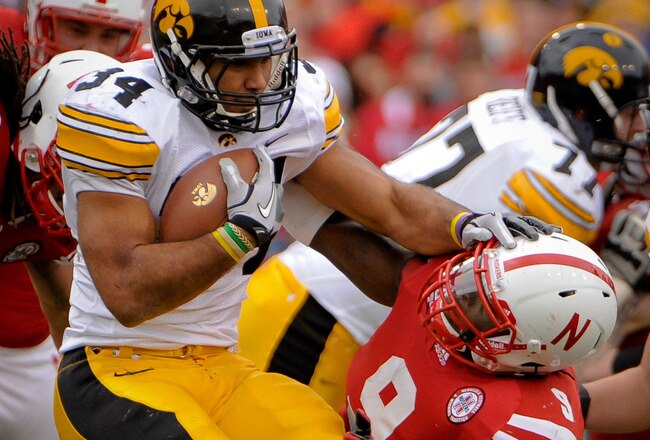 LINCOLN, NE - NOVEMBER 25: Running back Marcus Coker #34 of the Iowa Hawkeyes is wrapped up by defensive end Jason Ankrah #9 of the Nebraska Cornhuskers during their game at Memorial Stadium November 25, 2011 in Lincoln, Nebraska. Nebraska defeated Iowa 20-7. (Photo by Eric Francis/Getty Images)