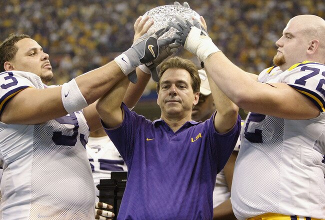 NEW ORLEANS - JANUARY 4:  Head coach Nick Saban of LSU holds up the National championship trophy with his players Chad Lavalais #93 and Stephen Peterman #72 after defeating Oklahoma 21-14 to win the National Championship at the Nokia Sugar Bowl on January 4, 2004 at the Louisiana Superdome in New Orleans, Louisiana.  (Photo by Brian Bahr/Getty Images)