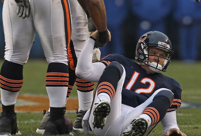 CHICAGO, IL - DECEMBER 04:  Caleb Hanie #12 of the Chicago Bears is helped to his feet by Lance Louis #60 after being sacked by the Kansas City Chiefs at Soldier Field on December 4, 2011 in Chicago, Illinois. The Chiefs defeated the Bears 10-3. (Photo by Jonathan Daniel/Getty Images)