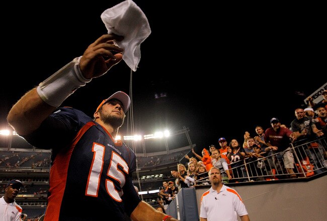 DENVER, CO - AUGUST 20:  Quarterback Tim Tebow #15 of the Denver Broncos throws a towel to a fan as he exits the field after a pre-season game against the Buffalo Bills at Sports Authority Field at Mile High on August 20, 2011 in Denver, Colorado. The Broncos defeated the Bills 24-10. (Photo by Justin Edmonds/Getty Images)