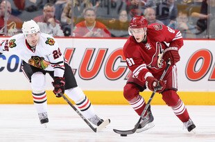 GLENDALE, AZ - FEBRUARY 12:  Kyle Turris #19 of the Phoenix Coyotes skates with the puck past Troy Brouwer #22 of the Chicago Blackhawks during the NHL game at Jobing.com Arena on February 12, 2011 in Glendale, Arizona. The Coyotes defeated the Blackhawks 3-2 in an overtime shootout.  (Photo by Christian Petersen/Getty Images)