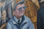 STATE COLLEGE, PA - NOVEMBER 11: People walk past the mural 'Inspiration' by artist Michael Pilato, which features faces of notable Penn Staters including Joe Paterno, in the wake of the Jerry Sandusky scandal on November 11, 2011 in State College, Pennsylvania. Sandusky was featured in the mural but was painted over this week by the artist. Head football coach Joe Paterno was fired amid allegations that former Penn State defensive coordinator Jerry Sandusky was involved with child sex abuse. Penn State plays their final home football game against Nebraska tomorrow at Beaver Stadium.  (Photo by Mario Tama/Getty Images)