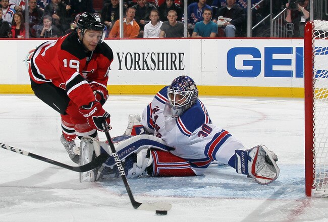 NEWARK, NJ - DECEMBER 20: Travis Zajac #19 of the New Jersey Devils tries the control the puck in front of Henrik Lundqvist #30 of the New York Rangers at the Prudential Center on December 20, 2011 in Newark, New Jersey.  (Photo by Bruce Bennett/Getty Images)