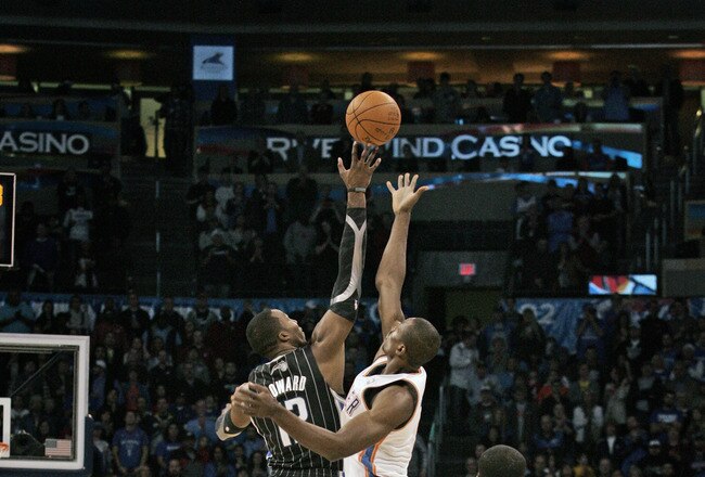 OKLAHOMA CITY, OK - DECEMBER 25:  Dwight Howard #12 of the Orlando Magic and Serge Ibaka #9 of the Oklahoma City Thunder jump for the ball at tip off during the NBA season opening game December 25, 2011 at the Chesapeake Energy Arena in Oklahoma City, Oklahoma.  Oklahoma City defeated Orlando 97-89. NOTE TO USER: User expressly acknowledges and agrees that, by downloading and or using this Photograph, user is consenting to the terms and conditions of the Getty Images License Agreement.  (Photo by Brett Deering/Getty Images)