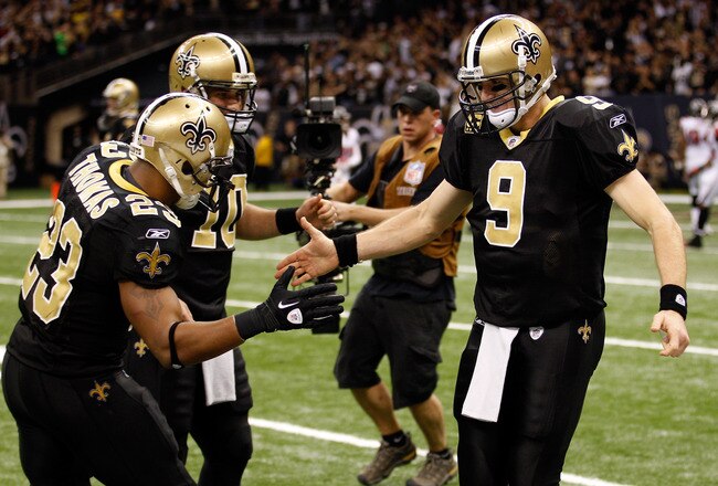 NEW ORLEANS, LA - DECEMBER 26:  (R) Quarterback Drew Brees #9 of the New Orleans Saints celebrates throwing a 24-yard third quarter touchdown pass with running back Pierre Thomas #23 and quarterback Chase Daniel #10 against the Atlanta Falcons at the Mercedes-Benz Superdome on December 26, 2011 in New Orleans, Louisiana.  (Photo by Chris Graythen/Getty Images)