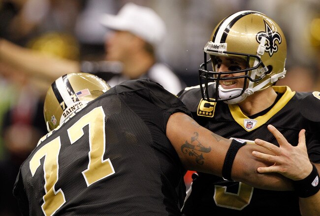 NEW ORLEANS, LA - DECEMBER 26:  Quarterback Drew Brees #9 of the New Orleans Saints is picked up by offensive guard Carl Nicks #77 after Brees throws a nine-yard touchdown pass to running back Darren Sproles #43 and breaks the single-season passing record in the fourth quarter against the Atlanta Falcons at the Mercedes-Benz Superdome on December 26, 2011 in New Orleans, Louisiana.  (Photo by Chris Graythen/Getty Images)