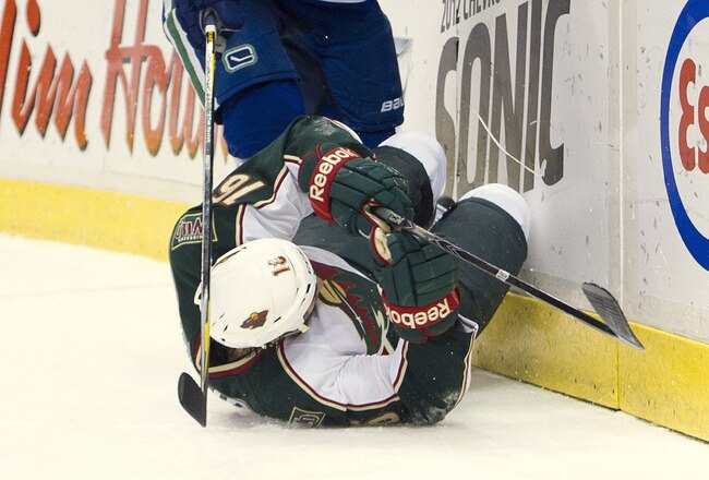 VANCOUVER, CANADA - DECEMBER 19: Alexander Sulzer #52 of the Vancouver Canucks knocks down Brad Staubitz #16 of the Minnesota Wild with a hit during the first period in NHL action on December 19, 2011 at Rogers Arena in Vancouver, British Columbia, Canada.  (Photo by Rich Lam/Getty Images)
