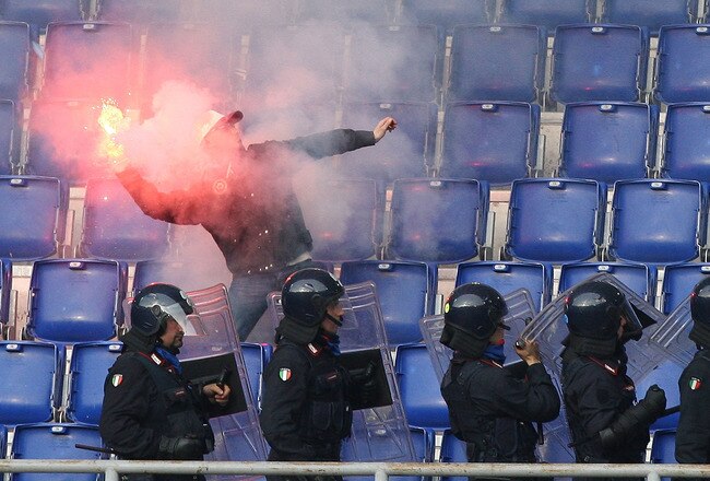 ROME - APRIL 18:  A football supporter throws a flare as Police move in on the stands before the Serie A match between SS Lazio and AS Roma at Stadio Olimpico on April 18, 2010 in Rome, Italy.  (Photo by Paolo Bruno/Getty Images)