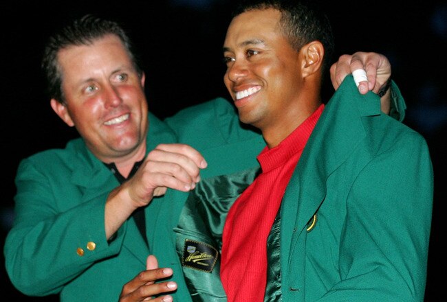 AUGUSTA, GA - APRIL 10:  Tiger Woods smiles as he is presented with the green jacket by Phil Mickelson after Woods won The Masters at the Augusta National Golf Club on April 10, 2005 in Augusta, Georgia.  (Photo by Harry How/Getty Images)