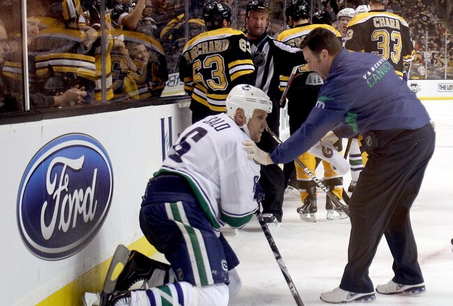 BOSTON, MA - JANUARY 07:  Sami Salo #6 of the Vancouver Canucks is helped off the ice after he was hit by Brad Marchand #63 of the Boston Bruins on January 7, 2012 at TD Garden in Boston, Massachusetts.  (Photo by Elsa/Getty Images)