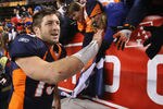 DENVER, CO - JANUARY 08:  Quarterback Tim Tebow #15 of the Denver Broncos receives high fives from fans after defeating the Pittsburgh Steelers in overtime of the AFC Wild Card Playoff game at Sports Authority Field at Mile High on January 8, 2012 in Denver, Colorado. The Broncos defeated the Steelers in overtime 23-29.  (Photo by Jeff Gross/Getty Images)