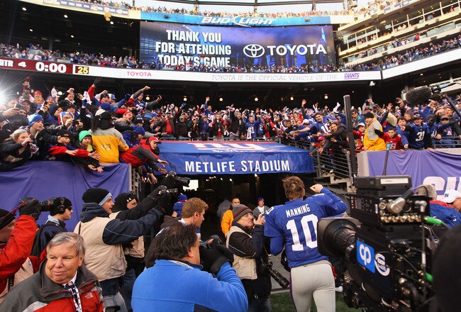 EAST RUTHERFORD, NJ - JANUARY 08:  Fans cheer as Eli Manning #10 of the New York Giants runs off of the field after the Giants won 24-2 against Atlanta Falcons during their NFC Wild Card Playoff game at MetLife Stadium on January 8, 2012 in East Rutherford, New Jersey.  (Photo by Al Bello/Getty Images)