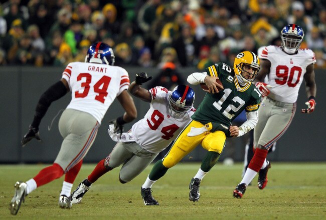 GREEN BAY, WI - JANUARY 15:  Aaron Rodgers #12 of the Green Bay Packers runs with the ball against  Mathias Kiwanuka #94 and Deon Grant #34 of the New York Giants during their NFC Divisional playoff game at Lambeau Field on January 15, 2012 in Green Bay, Wisconsin.  (Photo by Jamie Squire/Getty Images)