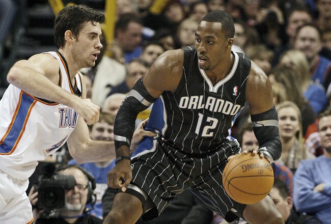 OKLAHOMA CITY, OK - DECEMBER 25:  Dwight Howard #12 of the Orlando Magic looks to drive on Nick Collison #4 of the Oklahoma City Thunder during the NBA season opening game December 25, 2011 at the Chesapeake Energy Arena in Oklahoma City, Oklahoma.  Oklahoma City defeated Orlando 97-89. NOTE TO USER: User expressly acknowledges and agrees that, by downloading and or using this Photograph, user is consenting to the terms and conditions of the Getty Images License Agreement.  (Photo by Brett Deering/Getty Images)