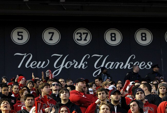 NEW YORK - DECEMBER 30:  Fans of the Rutgers Scarlet Knights cheer in front of the wall of retired New York Yankees numbers during the New Era Pinstripe Bowl against the Iowa State Cyclones at Yankee Stadium on December 30, 2011 in the Bronx Borough of New York City.  (Photo by Jeff Zelevansky/Getty Images)