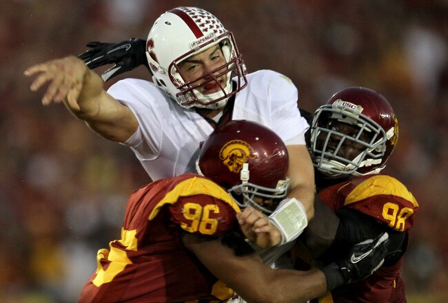 LOS ANGELES, CA - OCTOBER 29:  Quarterback Andrew Luck #12 of the Stanford Cardinal is hit after throwing a pass by defensive linemen Wes Horton #96 and Dajohn Harris #98 of the USC Trojans at the Los Angeles Memorial Coliseum on October 29, 2011 in Los Angeles, California.  (Photo by Stephen Dunn/Getty Images)