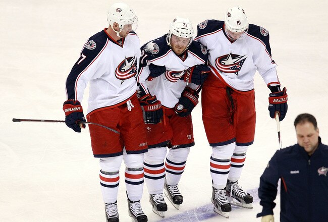 DALLAS, TX - DECEMBER 29:  James Wisniewski #21 of the Columbus Blue Jackets is helped off the ice by Jeff Carter #7 and Ryan Johansen #19 at American Airlines Center on December 29, 2011 in Dallas, Texas.  (Photo by Ronald Martinez/Getty Images)