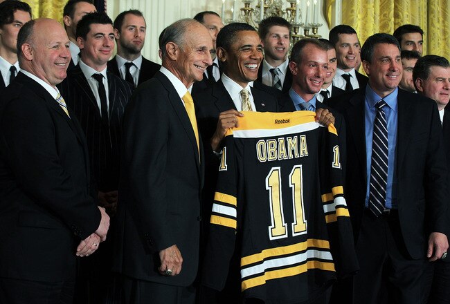 WASHINGTON, DC - JANUARY 23:  U.S. President Barack Obama (3rd L) poses for photos with members of the Boston Bruins (first row, L-R) head coach Claude Julien, team owner Jeremy Jacobs, Jacobs' son Charlie, team president of Cam Neely and assistant general manager Jim Benning after he was presented with a jersey by during a East Room event at the White House January 23, 2012 in Washington, DC. The six-time Stanley Cup champions were honored by the President for winning the 2011 Stanley Cup last June.  (Photo by Alex Wong/Getty Images)