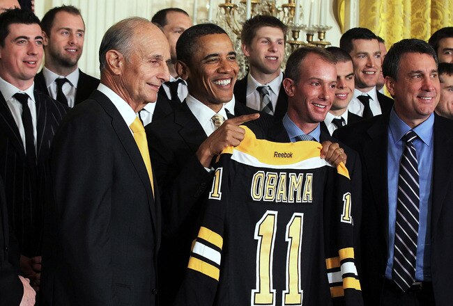 WASHINGTON, DC - JANUARY 23:  U.S. President Barack Obama (3rd L) poses for photos with members of the Boston Bruins (first row, L-R) head coach Claude Julien, team owner Jeremy Jacobs, Jacobs' son Charlie, team president of Cam Neely and assistant general manager Jim Benning after he was presented with a jersey by during a East Room event at the White House January 23, 2012 in Washington, DC. The six-time Stanley Cup champions were honored by the President for winning the 2011 Stanley Cup last June.  (Photo by Alex Wong/Getty Images)