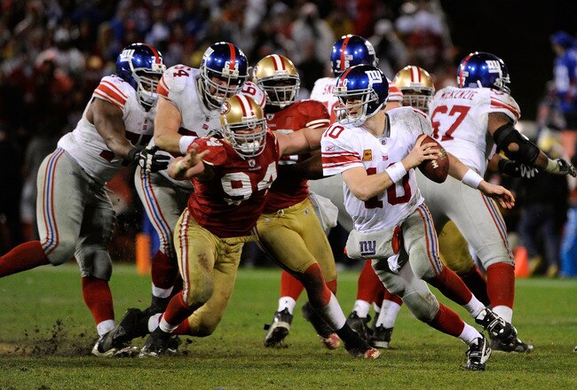 SAN FRANCISCO, CA - JANUARY 22:  Eli Manning #10 of the New York Giants attempts to avoid pressure from Justin Smith #94 of the San Francisco 49ers during the NFC Championship Game at Candlestick Park on January 22, 2012 in San Francisco, California.  (Photo by Thearon W. Henderson/Getty Images)