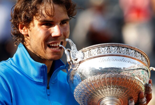 PARIS, FRANCE - JUNE 05:  Champion Rafael Nadal of Spain bites the trophy following his record equalling sixth victory during the men's singles final match between Rafael Nadal of Spain and Roger Federer of Switzerland on day fifteen of the French Open at Roland Garros on June 5, 2011 in Paris, France.  (Photo by Matthew Stockman/Getty Images)