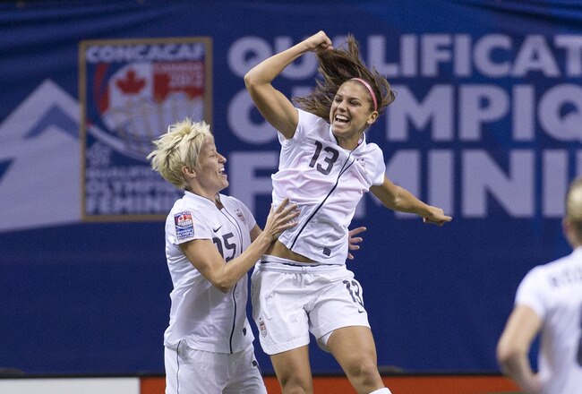 VANCOUVER, CANADA - JANUARY 29:  Alex Morgan #13 of the United States celebrates with Mega Rapinoe #15 after scoring against Canada during the first half of championship action of the 2012 CONCACAF Women's Olympic Qualifying Tournament at BC Place on January 29, 2012 in Vancouver, British Columbia, Canada.  (Photo by Rich Lam/Getty Images)