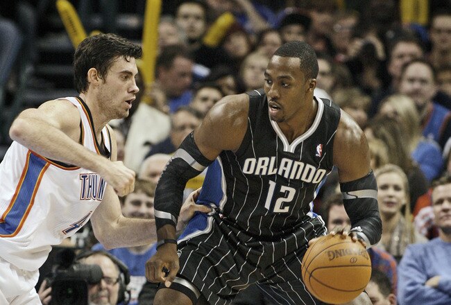 OKLAHOMA CITY, OK - DECEMBER 25:  Dwight Howard #12 of the Orlando Magic looks to drive on Nick Collison #4 of the Oklahoma City Thunder during the NBA season opening game December 25, 2011 at the Chesapeake Energy Arena in Oklahoma City, Oklahoma.  Oklahoma City defeated Orlando 97-89. NOTE TO USER: User expressly acknowledges and agrees that, by downloading and or using this Photograph, user is consenting to the terms and conditions of the Getty Images License Agreement.  (Photo by Brett Deering/Getty Images)