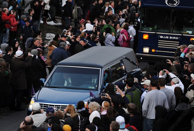 STATE COLLEGE, PA - JANUARY 25: Mourners line the sidewalks of College Avenue on the campus of Penn State, as the procession carries former Penn State Football coach Joe Paterno from the Pasquerilla Spiritual Center to his burial site, January 25, 2012 in State College, Pennsylvania. Paterno, who was 85, died due to complications from lung cancer on January 22, 2012. (Photo by Patrick Smith/Getty Images)