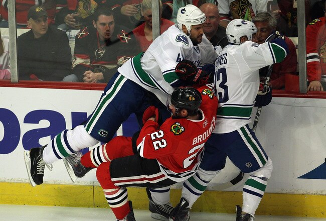 CHICAGO, IL - APRIL 24: Andrew Alberts #41 of the Vancouver Canucks hits Troy Brouwer #22 of the Chicago Blackhawks as teammate Raffi Tores #13 moves to the puck in Game Six of the Western Conference Quarterfinals during the 2011 NHL Stanley Cup Playoffs at the United Center on April 24, 2011 in Chicago, Illinois. The Blackhawks defeated the Canucks 4-3 in sudden death overtime. (Photo by Jonathan Daniel/Getty Images)