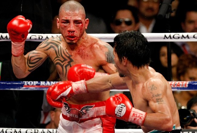 LAS VEGAS - NOVEMBER 14:  A bloodied Miguel Cotto (L) and Manny Pacquiao battle during the 11th round of their WBO welterweight title fight at the MGM Grand Garden Arena on November 14, 2009 in Las Vegas, Nevada. Pacquiao defeated Cotto by TKO in the 12th round.  (Photo by Ethan Miller/Getty Images)