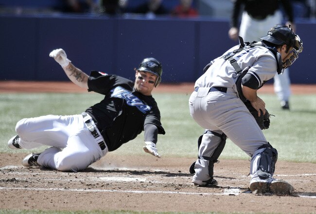 TORONTO, CANADA - SEPTEMBER 17:  Brett Lawrie #13 of the Toronto Blue Jays slides into safely into home as Austin Romine #71 of the New York Yankees covers the plate during MLB game action September 17, 2011 at Rogers Centre in Toronto, Ontario, Canada. (Photo by Brad White/Getty Images)