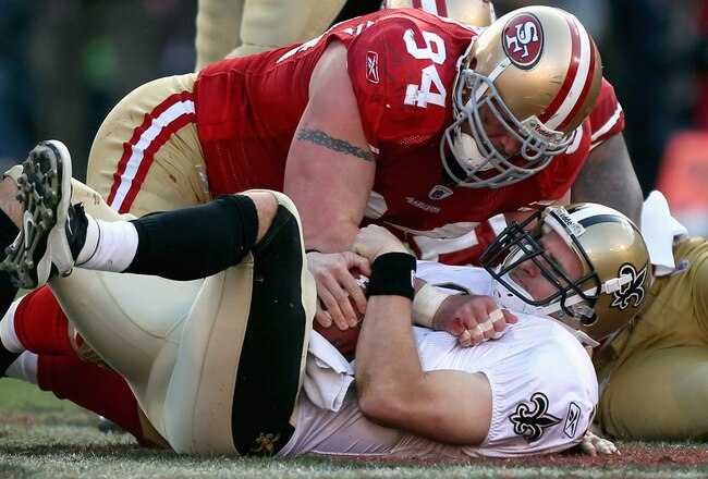 SAN FRANCISCO, CA - JANUARY 14:  Justin Smith #94 of the San Francisco 49ers hovers over Drew Brees #9 of the New Orleans Saints after Brees was sacked in the third quarter of the NFC Divisional playoff game at Candlestick Park on January 14, 2012 in San Francisco, California.  (Photo by Jed Jacobsohn/Getty Images)