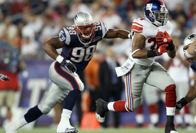FOXBORO, MA - SEPTEMBER 01:   Deon Grant #34 of the New York Giants carries the ball as  Eric Moore #98 of the New England Patriots defends on September 1, 2011 at Gillette Stadium in Foxboro, Massachusetts.  (Photo by Elsa/Getty Images)