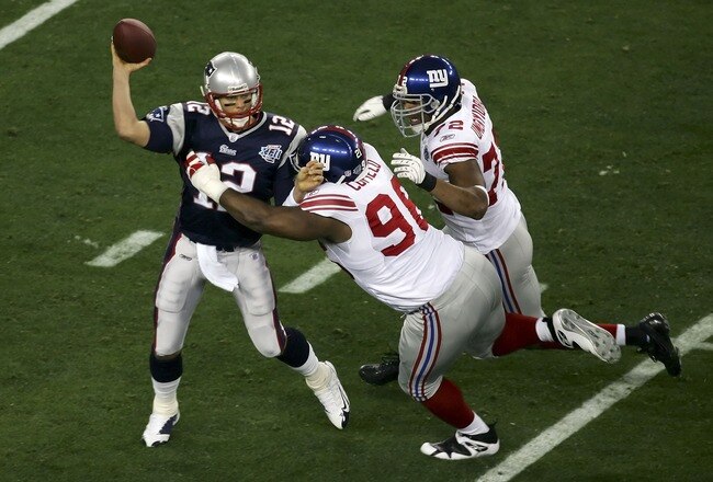 GLENDALE, AZ - FEBRUARY 03:  Quarterback Tom Brady #12 of the New England Patriots is hit as he throws by defensive tackle Barry Cofield #96 and Osi Umenyiora #72 of the New York Giants in the first half during Super Bowl XLII on February 3, 2008 at the University of Phoenix Stadium in Glendale, Arizona.  (Photo by Jim McIsaac/Getty Images)