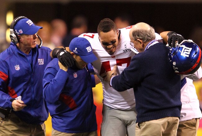 INDIANAPOLIS, IN - FEBRUARY 05:  Tight end Travis Beckum #47 of the New York Giants gets assisted off the field after injuring his ACL during the game against the New England Patriots in the second quarter during Super Bowl XLVI at Lucas Oil Stadium on February 5, 2012 in Indianapolis, Indiana.  (Photo by Al Bello/Getty Images)