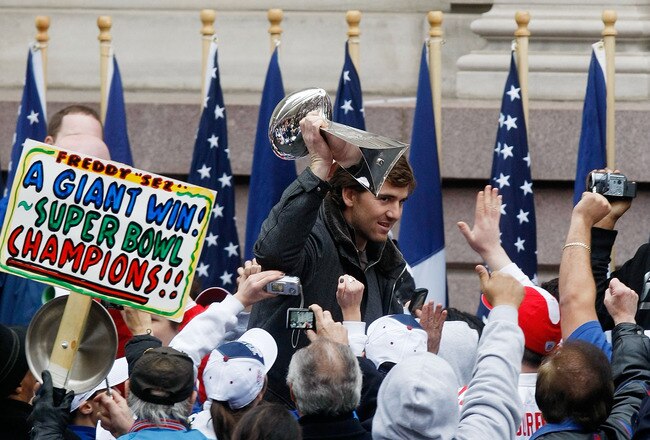 NEW YORK - FEBRUARY 05:  Quarterback Eli Manning holds the Vince Lombardi trophy up as he takes the stage during the New York Giants Super Bowl XLII victory parade reception at City Hall February 5, 2008 in New York City.  (Photo by Nick Laham/Getty Images)
