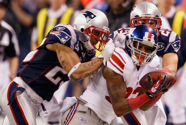INDIANAPOLIS, IN - FEBRUARY 05:  Mario Manningham #82 of the New York Giants makes a catch on the sidelines against Patrick Chung #25 and Sterling Moore #29 of the New England Patriots for a gain of 39 yards in the fourth quarter during Super Bowl XLVI at Lucas Oil Stadium on February 5, 2012 in Indianapolis, Indiana.  (Photo by Rob Carr/Getty Images)