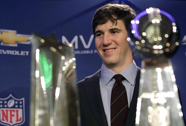 INDIANAPOLIS, IN - FEBRUARY 06:  In this General Motors handout, Eli Manning #10 of the New York Giants poses with the Super Bowl Championship Lombardi Trophy (right) and the Pete Rozelle Trophy for being the Super Bowl XLVI Most Valuable Player after defeating the New England Patriots during Super Bowl XLVI on February 6, 2012 in Indianapolis, Indiana. Manning, named MVP, led the Giants to a 21-17 victory.  (Photo by AJ Mast/General Motors via Getty Images)