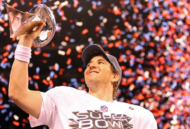 INDIANAPOLIS, IN - FEBRUARY 05:  Quarterback Eli Manning #10 of the New York Giants poses with the Vince Lombardi Trophy after the Giants defeated the Patriots by a score of 21-17 in Super Bowl XLVI at Lucas Oil Stadium on February 5, 2012 in Indianapolis, Indiana.  (Photo by Ezra Shaw/Getty Images)