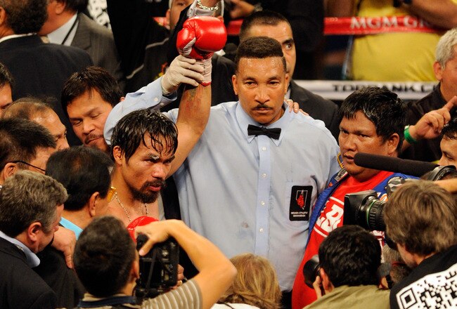 LAS VEGAS, NV - NOVEMBER 12:  Manny Pacquiao celebrates his majority decision victory with referee Tony Weeks against Juan Manuel Marquez in the WBO world welterweight title fight at the MGM Grand Garden Arena on November 12, 2011 in Las Vegas, Nevada.  (Photo by Ethan Miller/Getty Images)