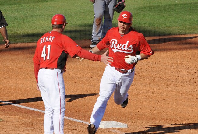 GOODYEAR, AZ - MARCH 02:  Devin Mesoraco #65 of the Cincinnati Reds rounds third base and is high fived by third base coach Mark Berry #41 after hitting a home run against the Chicago White Sox at Goodyear Ballpark on March 2, 2011 in Goodyear, Arizona.  (Photo by Norm Hall/Getty Images)