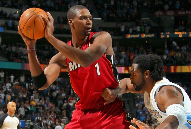 DENVER, CO - JANUARY 13:  Chris Bosh #1 of the Miami Heat controls the ball against the defense of Nene Hilario #31 of the Denver Nuggets at the Pepsi Center on January 13, 2012 in Denver, Colorado. The Nuggets defeated the Heat 117-104. NOTE TO USER: User expressly acknowledges and agrees that, by downloading and or using this photograph, User is consenting to the terms and conditions of the Getty Images License Agreement.  (Photo by Doug Pensinger/Getty Images)